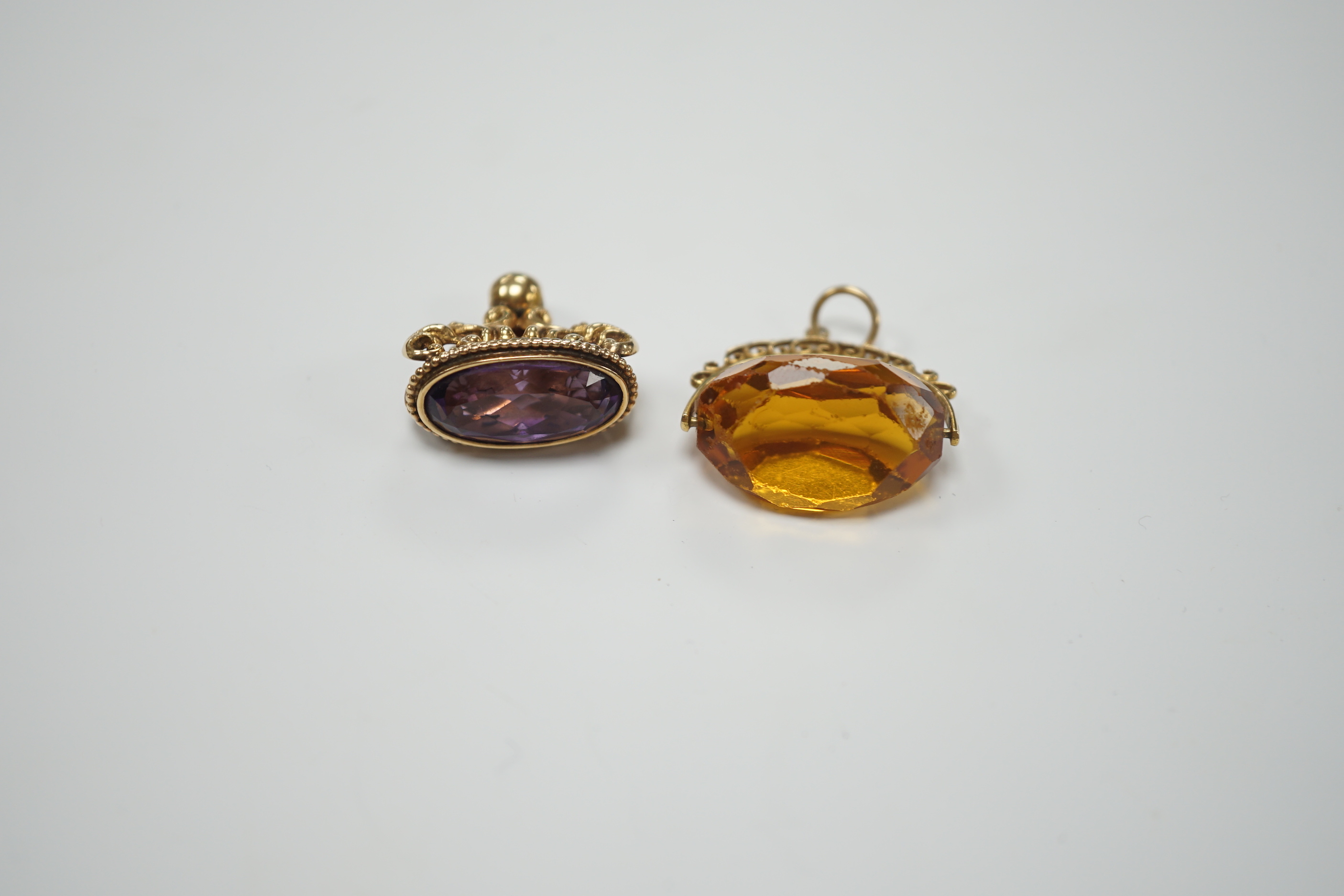 A yellow metal and amethyst set spinning fob, 22mm and one other 9ct gold and gem set fob, gross weight 15.5 grams.